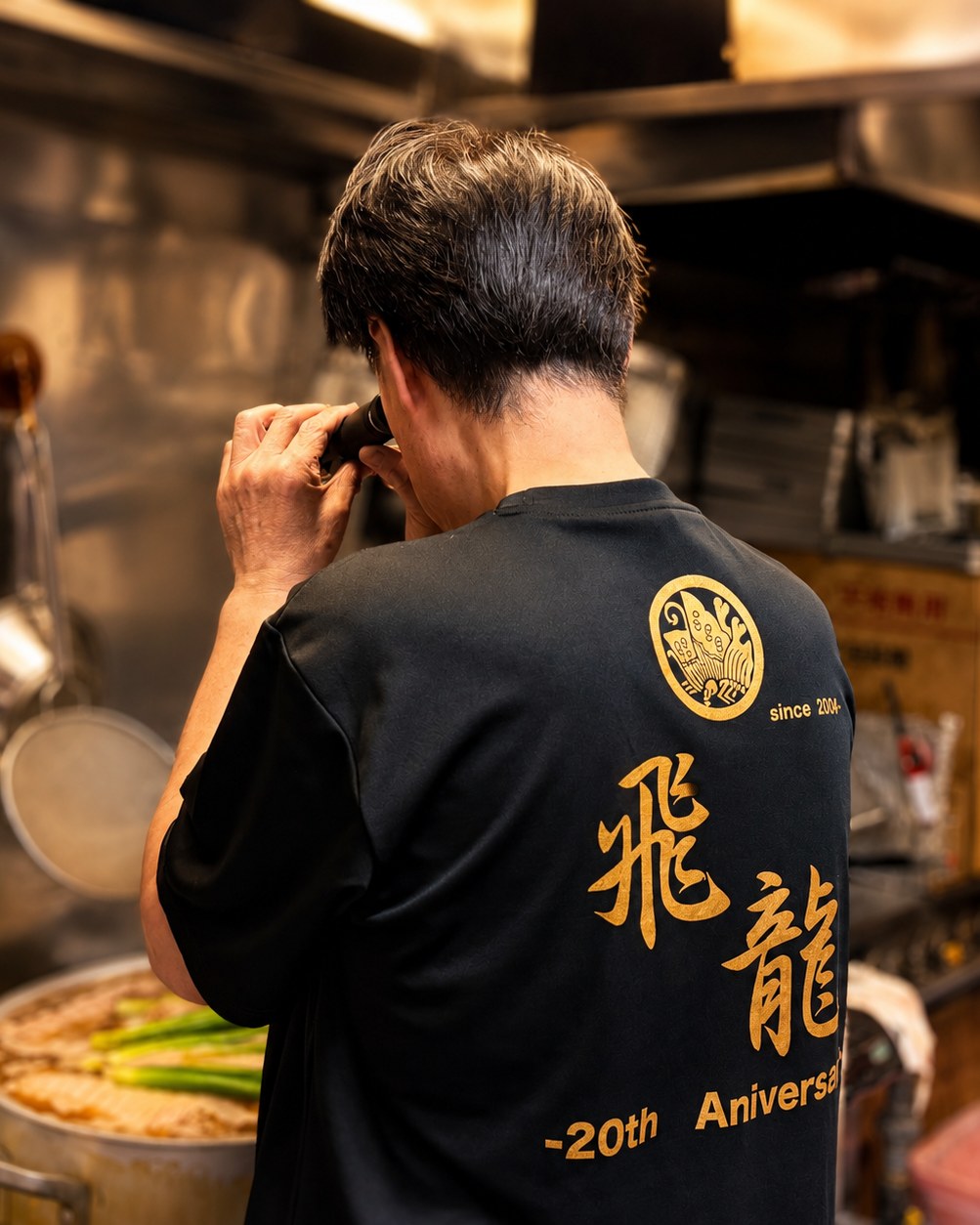 厨房でスープの味をみる店主